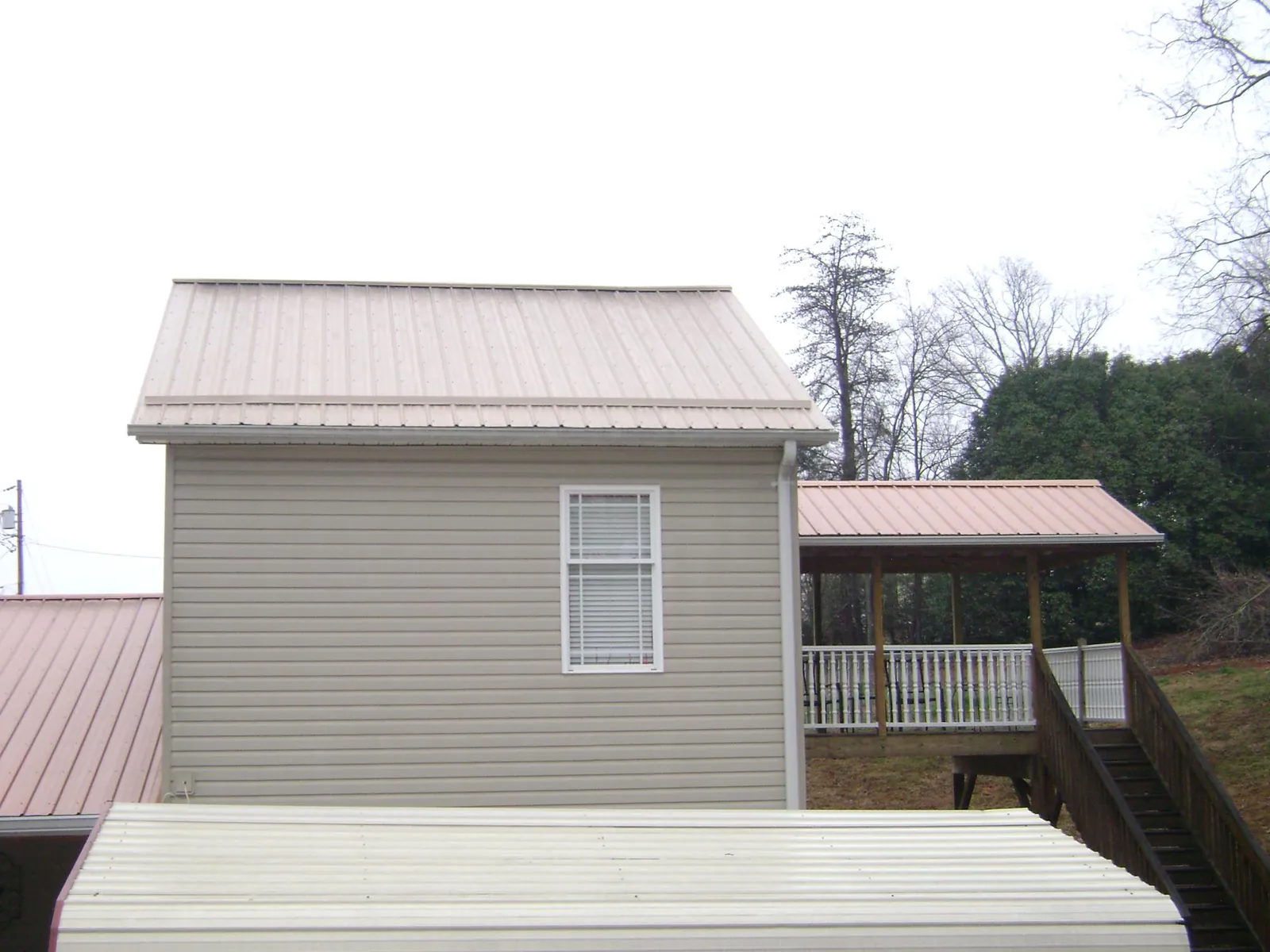 Tan metal roofs on a two story addition and attached porch, from a Roof Replacement job in Marathon